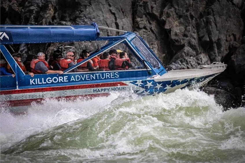 A boat with passengers wearing life jackets labeled 'Killgore Adventures' and 'Happy Hour' navigating through rough waters. 1