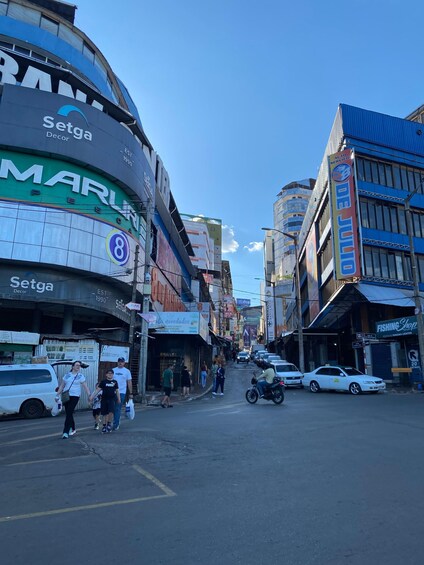 A bustling urban street with commercial buildings, a visible 'Setga Decor' sign, and a 'FISHING Shop' on the right. 3