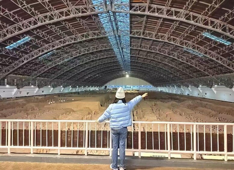 A person standing in an open stadium with a metal roof structure. 4