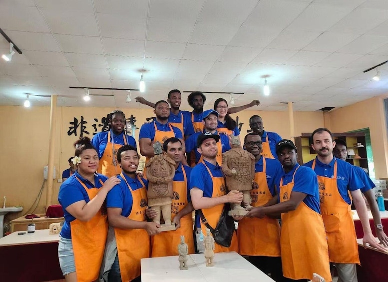 A group of people in blue shirts and orange aprons posing with a statue. 2