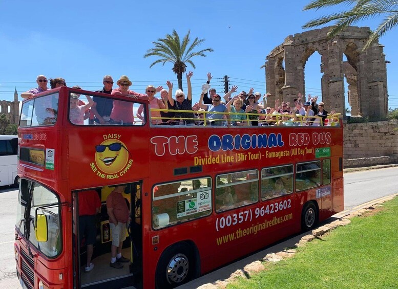 A red double-decker bus with passengers, advertising a tour of Famagusta. 1
