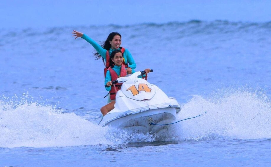 Two people on a jet ski, one wearing a life jacket, in a body of water. 3