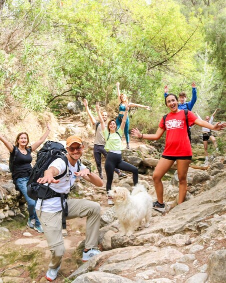 A group of hikers on a rocky trail surrounded by greenery. 2