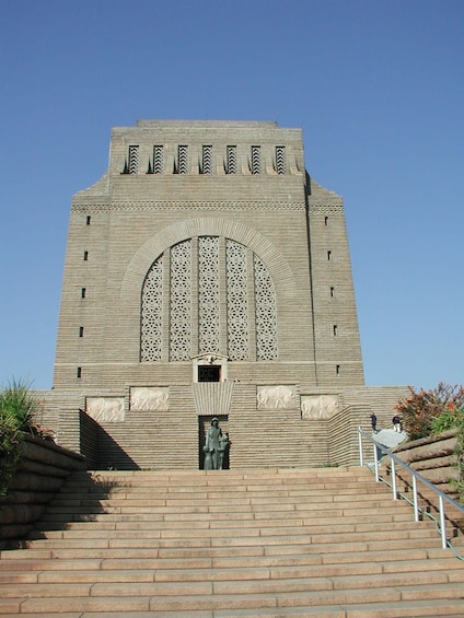 A large, ornate building with a central arched window and a statue at the entrance. 3
