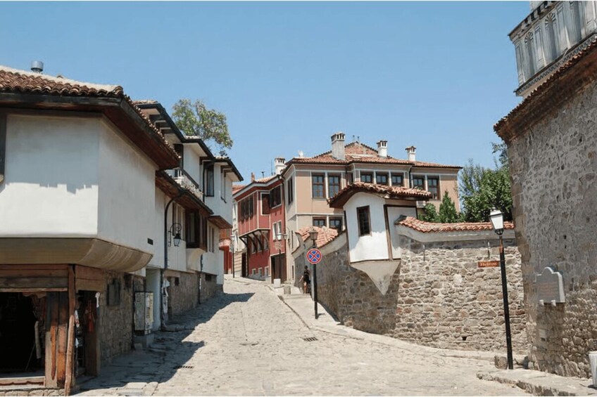 A narrow cobblestone street flanked by historic buildings with terracotta roofs and stone walls. 4