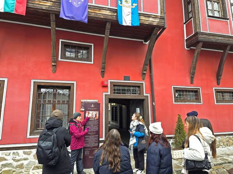 A red building with wooden beams, a signboard, and flags. 5