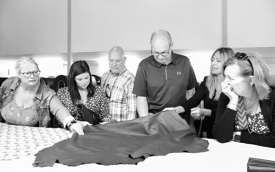 A group of people examining a large piece of fabric laid out on a table. 4