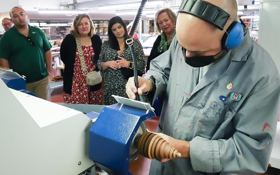 A person operating a blue machine with a rotating component, surrounded by onlookers. 3