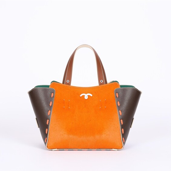 A brown leather handbag with an orange front panel and a white logo. 2