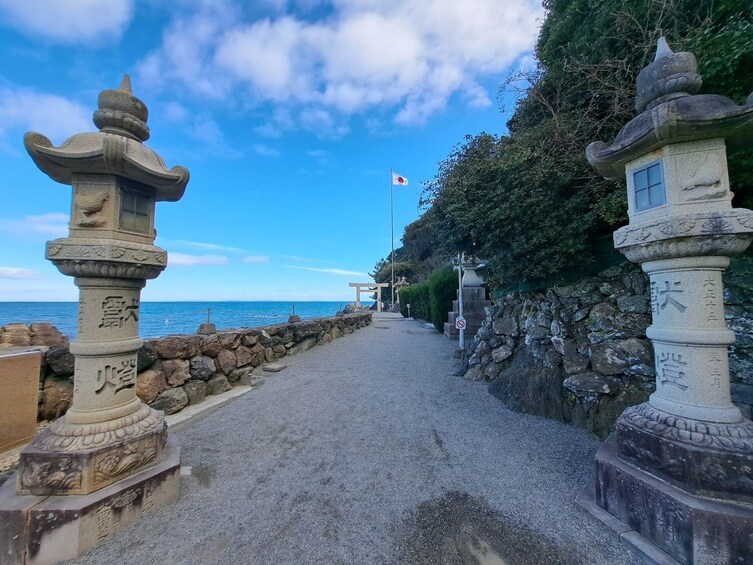 A pathway flanked by stone lanterns leading to a traditional Japanese torii gate. 2