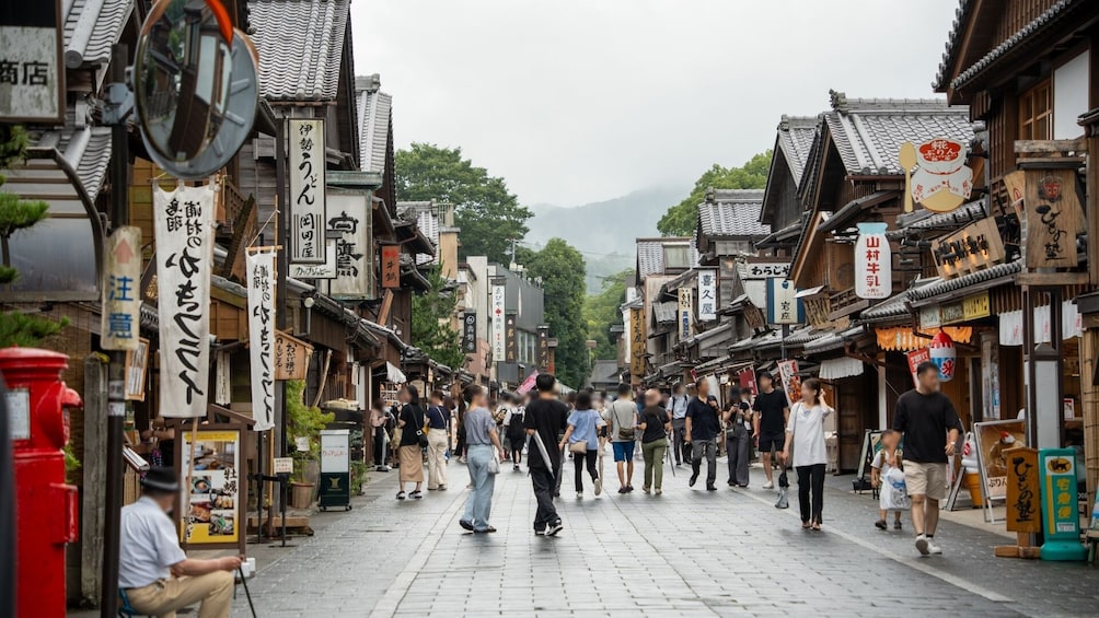 A bustling street in a traditional Japanese town with wooden buildings and signs in Japanese. 4