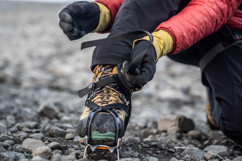 A person wearing hiking boots with laces and a strap, standing on a rocky surface. 5