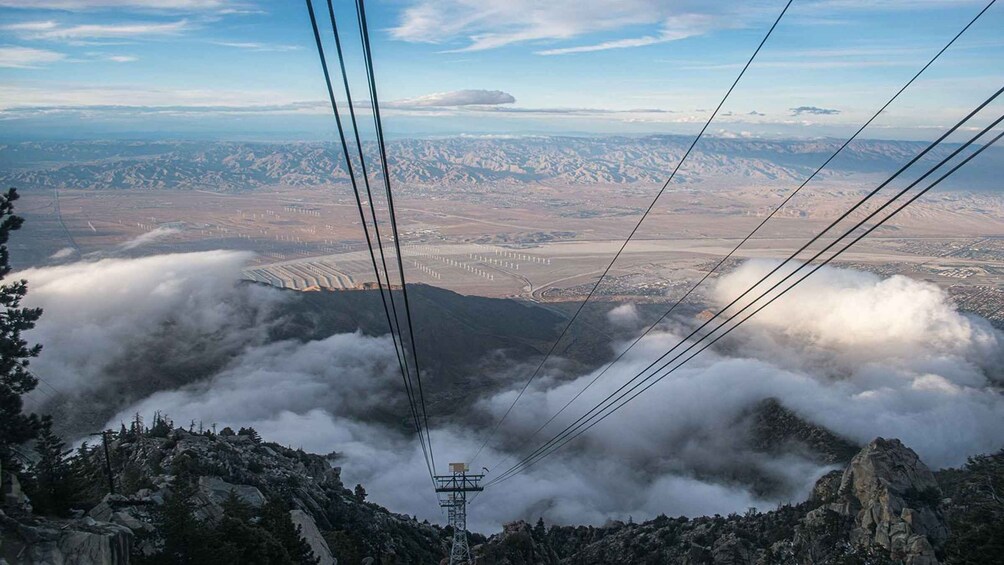A mountainous landscape with power lines, a valley, and a distant city. 4