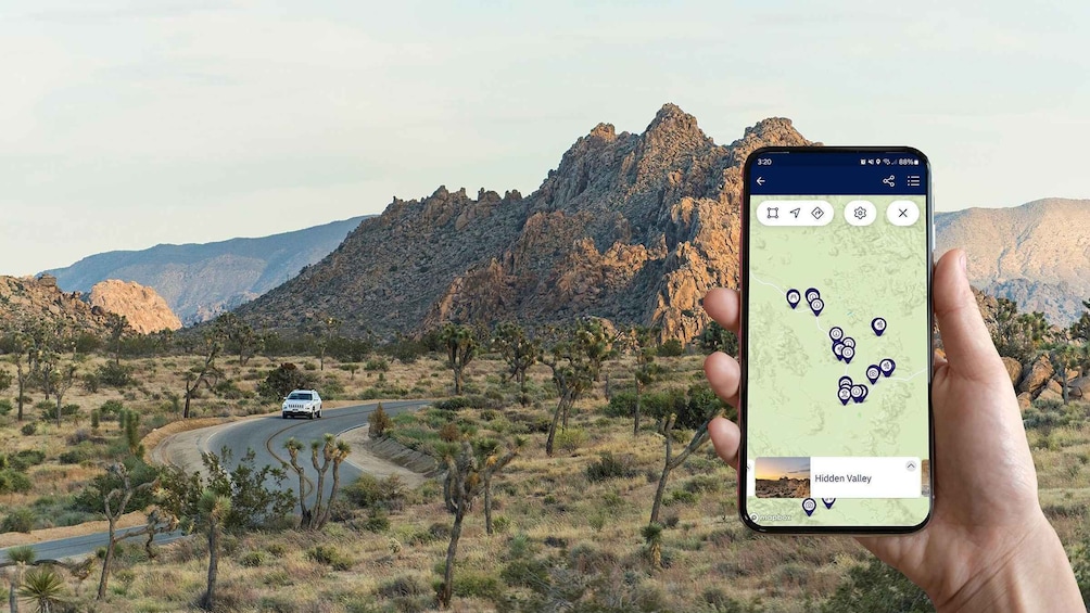 A smartphone displaying a map with location markers, a winding road, and a mountainous landscape. 1