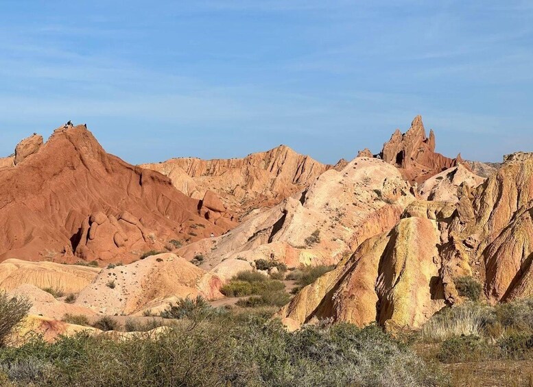 A rugged desert landscape with prominent red rock formations and sparse vegetation. 1