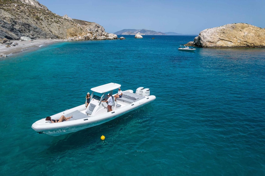 A white motorboat with passengers on a clear turquoise sea, surrounded by rocky cliffs and distant mountains. 5