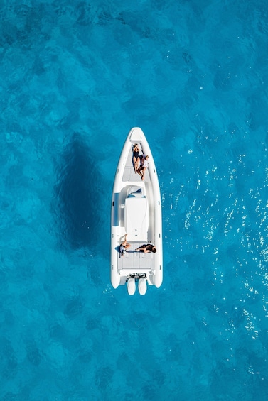 A white boat with two people on board, floating on clear blue water. 4