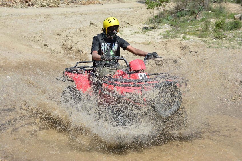A person riding a red ATV on a dirt path. 5