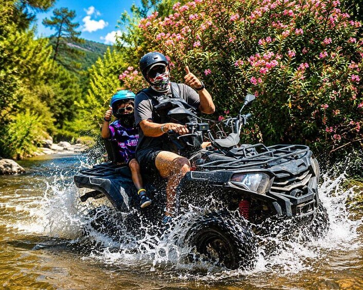 A person and a child on a quad bike crossing a river. 2