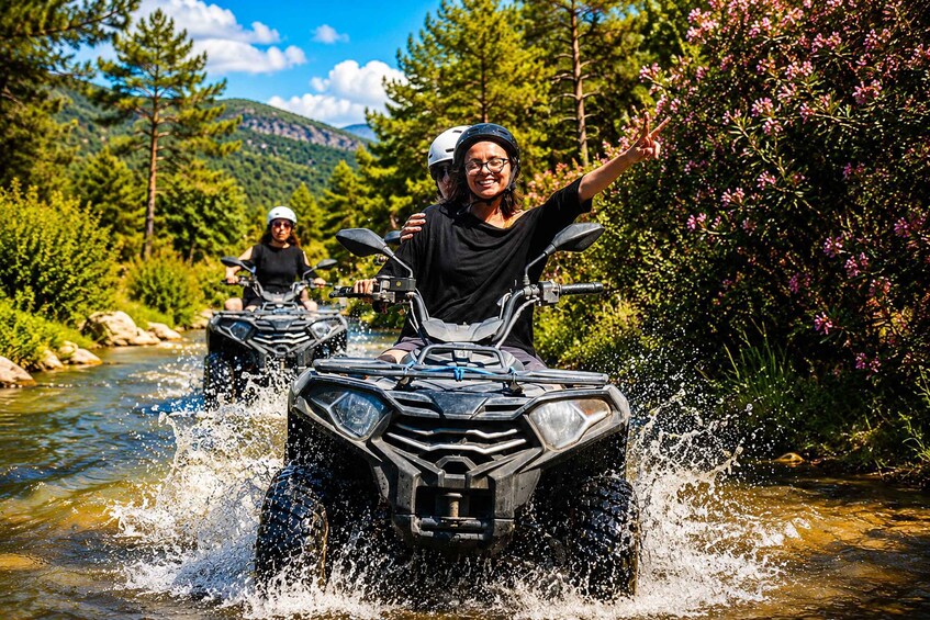 Two people riding all-terrain vehicles (ATVs) on a river surrounded by greenery and hills. 5