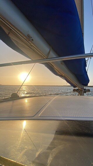 A sailboat's deck with a view of the ocean and the sun setting in the distance. 2
