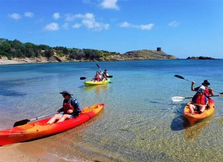 Three kayaks on calm water with clear skies and a rocky shoreline. 2