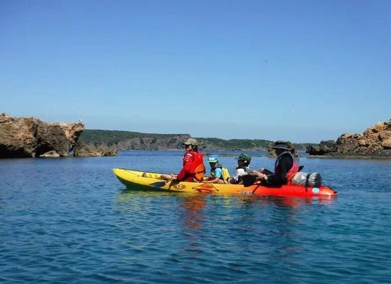 A group of people kayaking on a calm body of water with rocky cliffs in the background. 3