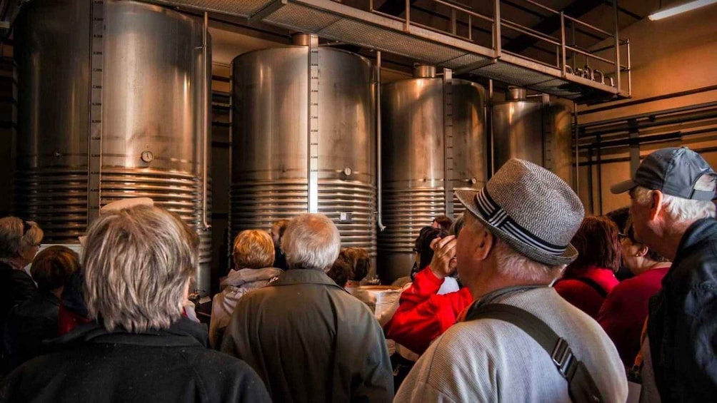 A group of people in a facility with large stainless steel tanks. 3