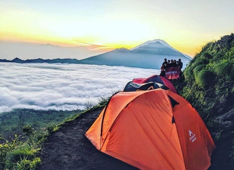 A tent on a mountain path with a view of a mountain and clouds. 2
