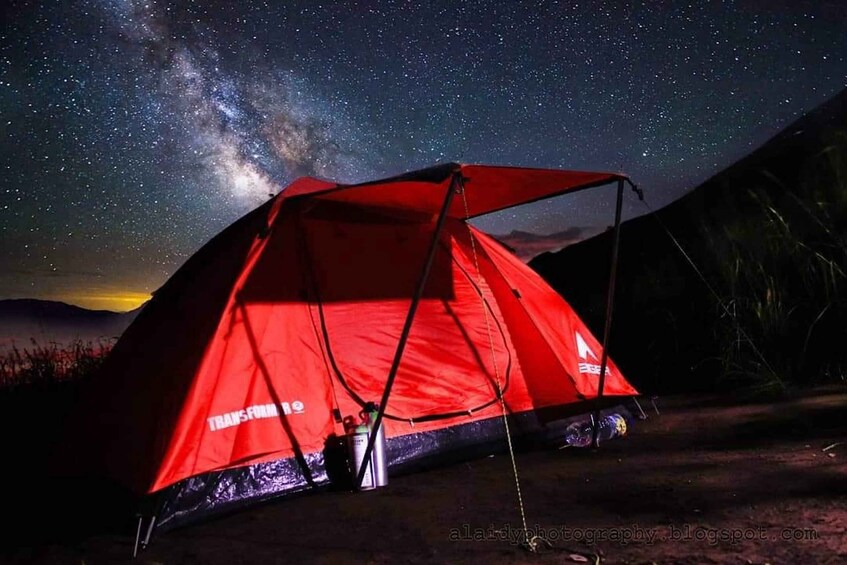 A red tent with 'TRANSFORMe' branding set up under a starry night sky. 5