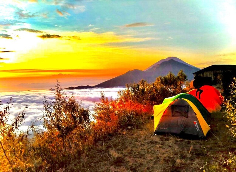 A tent on a grassy field with a mountain in the background and a sunrise. 4