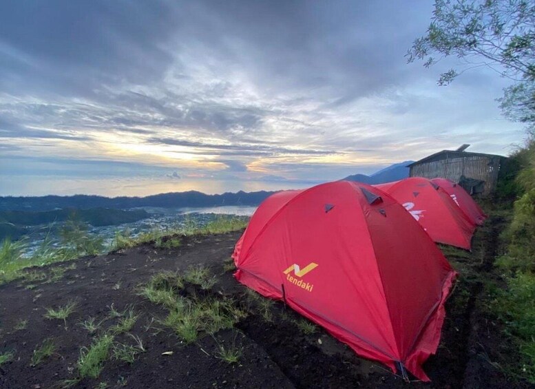 Red tents labeled 'tendaki' on a hillside with a view of a valley and mountains in the background. 3