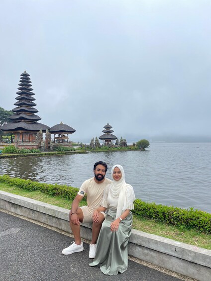 A couple sitting by a lake with traditional Balinese temples in the background. 3