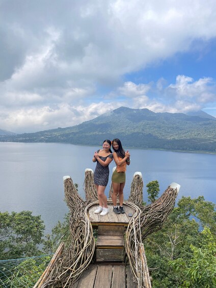 Two people standing on a wooden platform with a lake and mountains in the background. 5