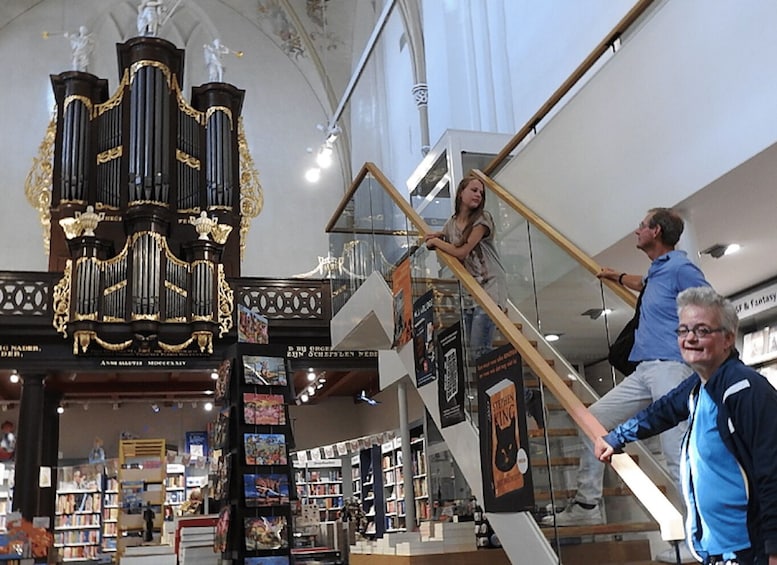 A bookstore with a grand organ, a staircase, and a glass railing. 4
