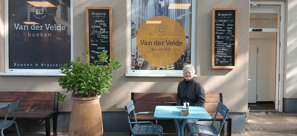 A cafe named Van der Velde with outdoor seating and a large potted plant. 3