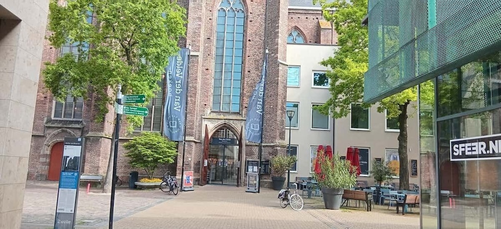 A building with large windows and a brick facade, surrounded by trees and outdoor seating. 5