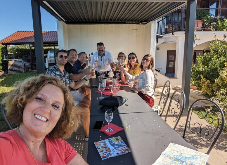A group of people seated at an outdoor table with drinks, under a covered patio area. 4
