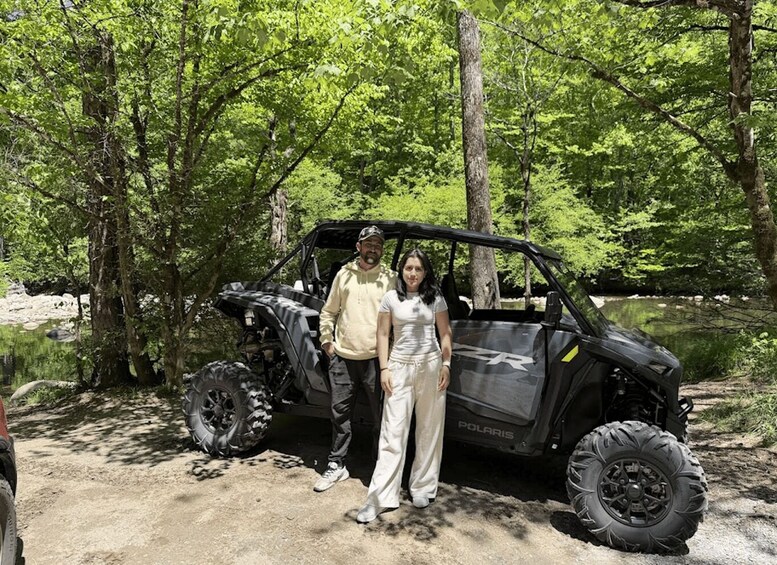A Polaris off-road vehicle in a wooded area with a river in the background. 3