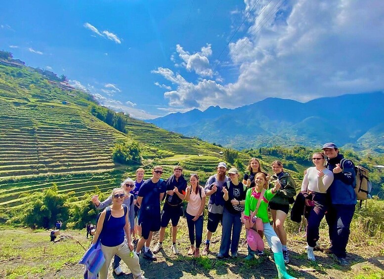A group of people standing on a hillside with terraced fields and mountains in the background. 2