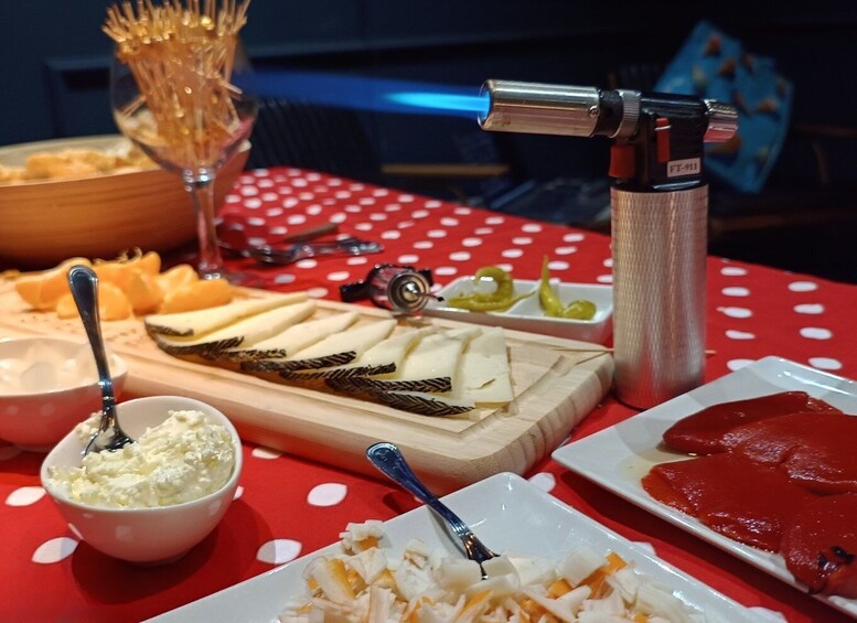 A charcuterie board with various cheeses, cured meats, and accompaniments on a red tablecloth. 4
