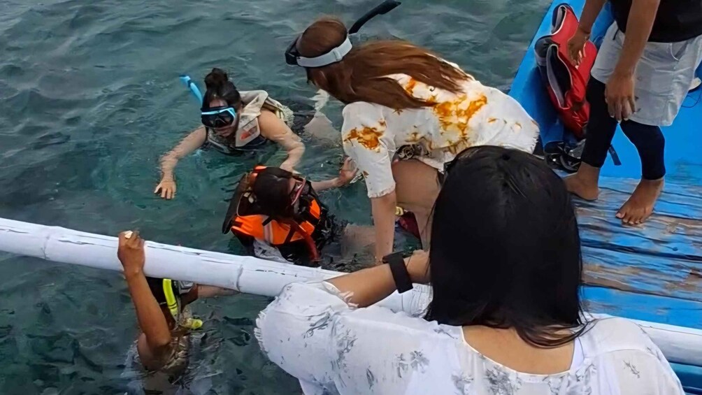 People in the water with scuba gear, a boat, and a person in a white shirt. 3
