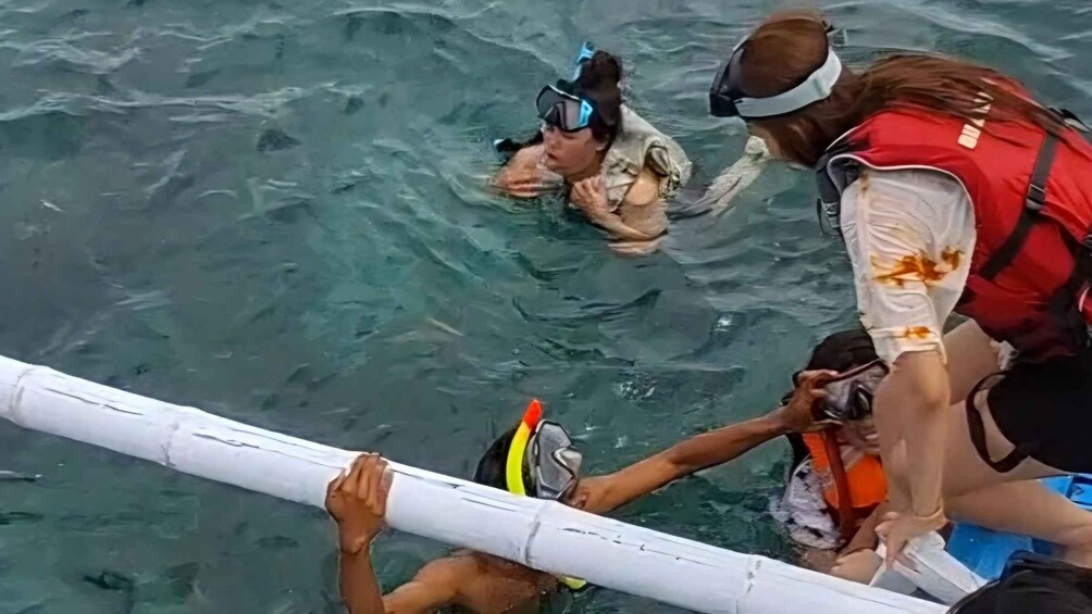 A group of people in a boat, some wearing life jackets and snorkeling gear. 2