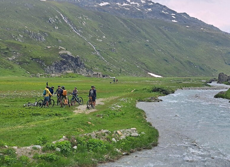 A group of cyclists on a trail with a river and mountains in the background. 3