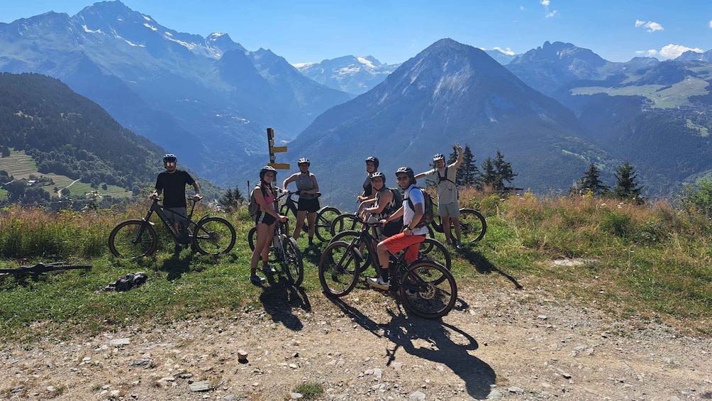 A group of cyclists on a mountain trail with a scenic view of snow-capped mountains in the background. 2