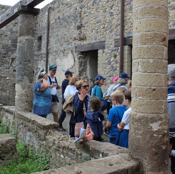 A group of tourists at an ancient stone building with steps leading up to it. 2