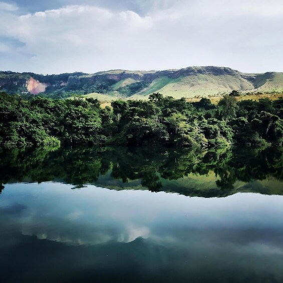 A calm lake reflecting the surrounding hills and dense greenery. 2