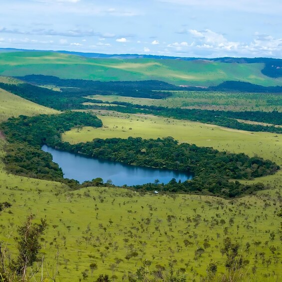 A lake surrounded by green hills and a clear sky. 4