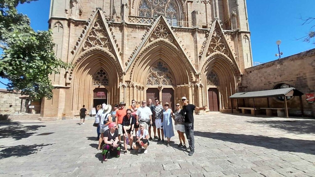 A group of people in front of a Gothic-style cathedral with intricate stonework and pointed arches. 2