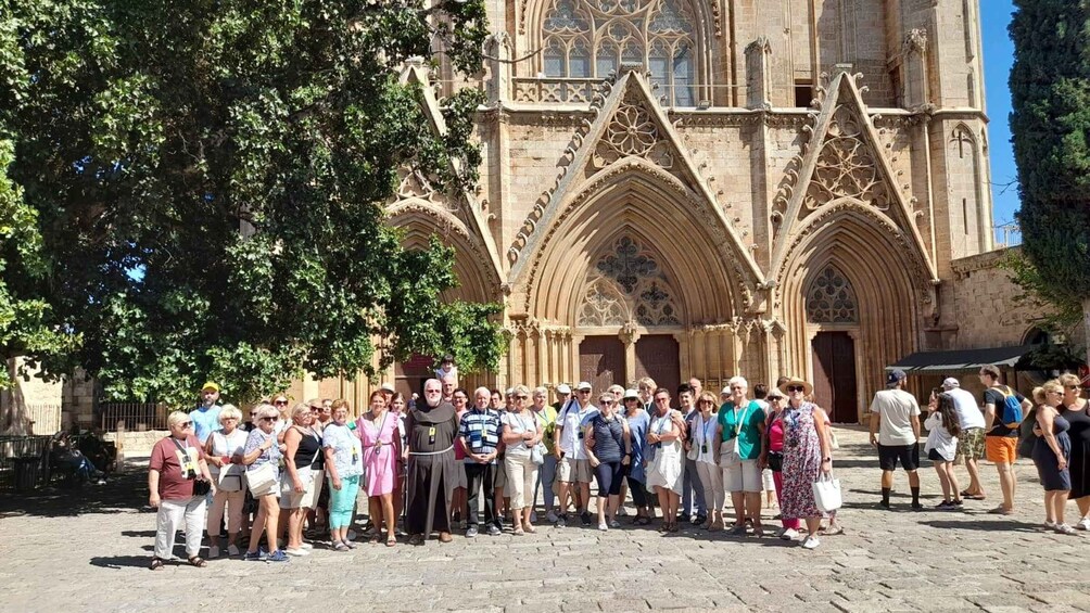 A group of people standing in front of a Gothic-style cathedral with pointed arches and intricate stonework. 3